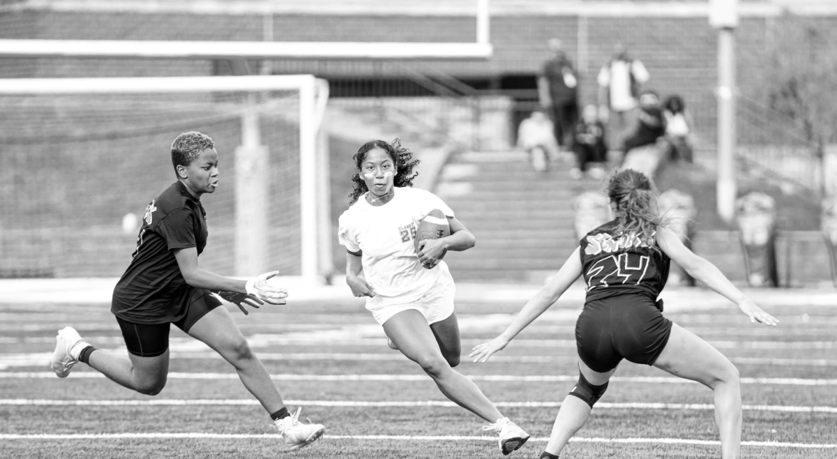 TRADING SNEAKERS FOR CLEATS - Junior track star Indie Wallace running through her opponents during the junior vs. senior powderpuff game.