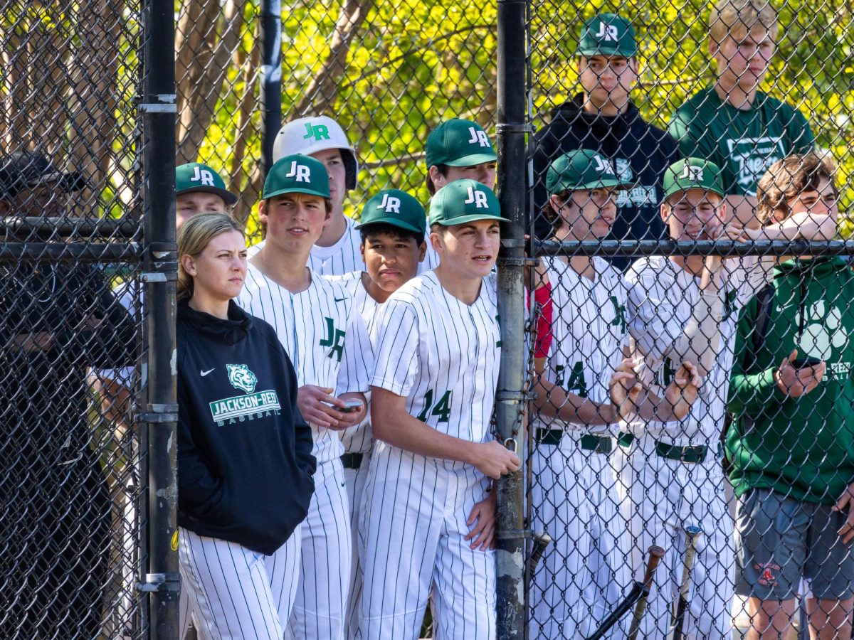 CAUGHT COACHING- Kelliann Jenkins stands among members of the boys’ varsity baseball team during a game. Jenkins is the team’s new pitching coach.