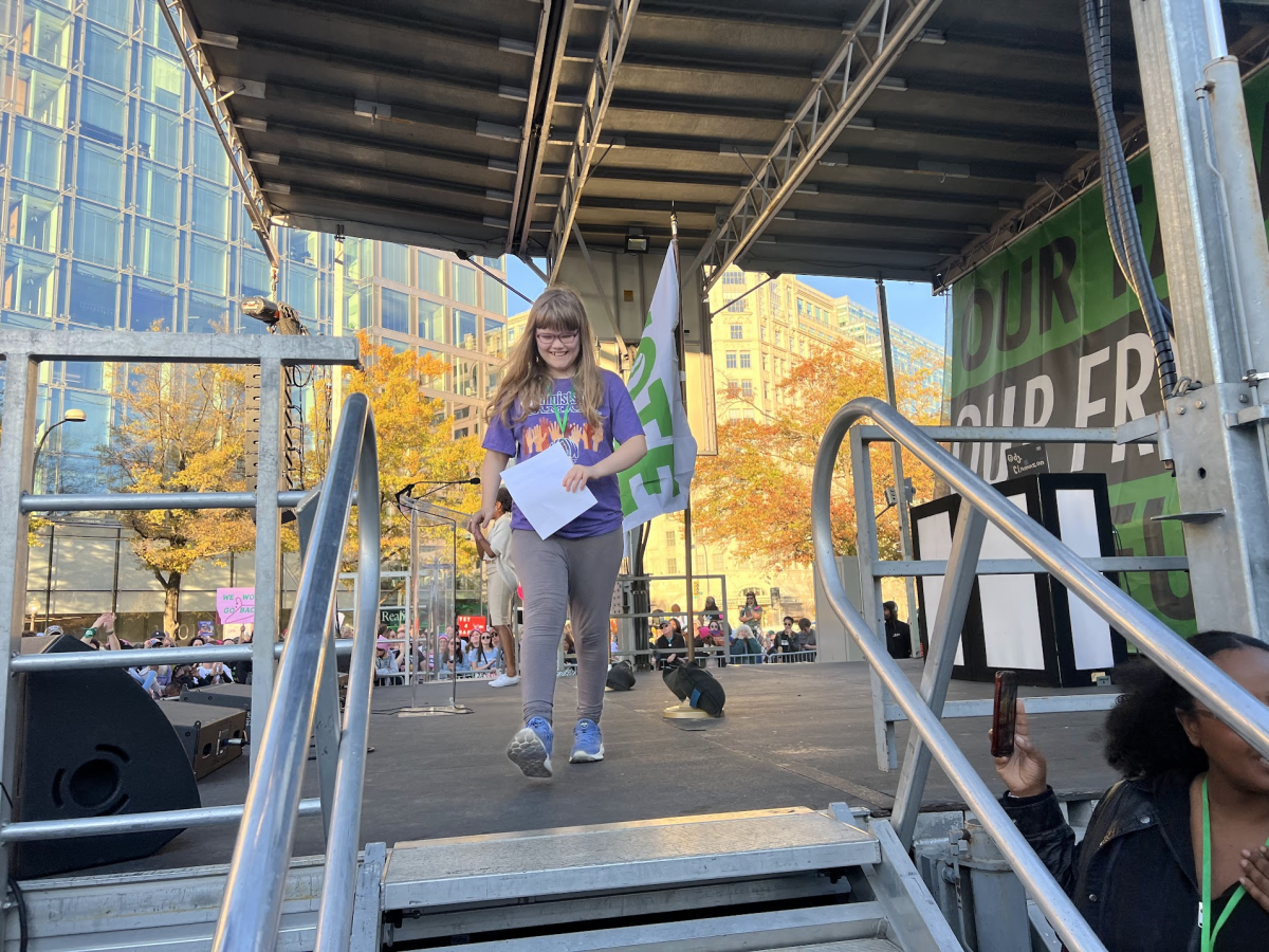 SMILING ON STAGE - Edie Young walks off stage after speaking at the Women's March on November 2nd. In her speech, Young discusses topics such as abortion rights and trans rights.